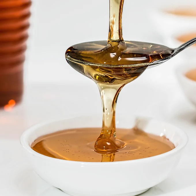 Photo of some honey being poured onto a spoon and a white bowl