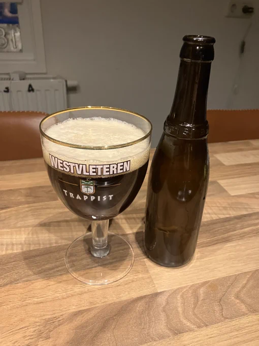 A glass of Westvleteren 12 that was just poured, next to a label-less bottle.