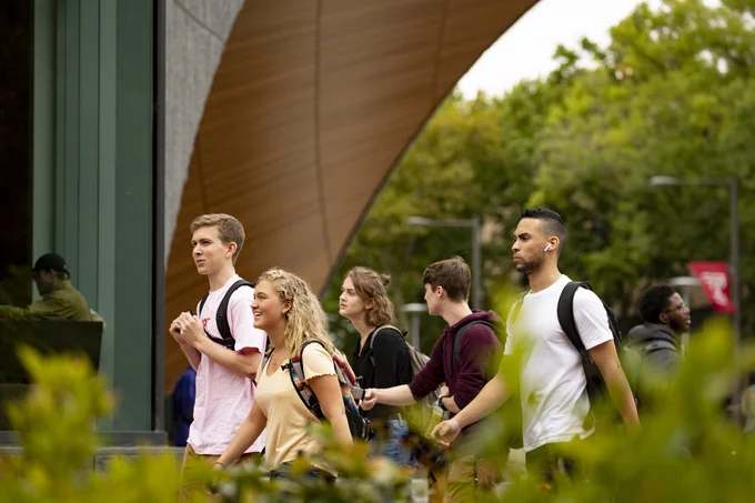 side view of 5 people walking in front of charles library