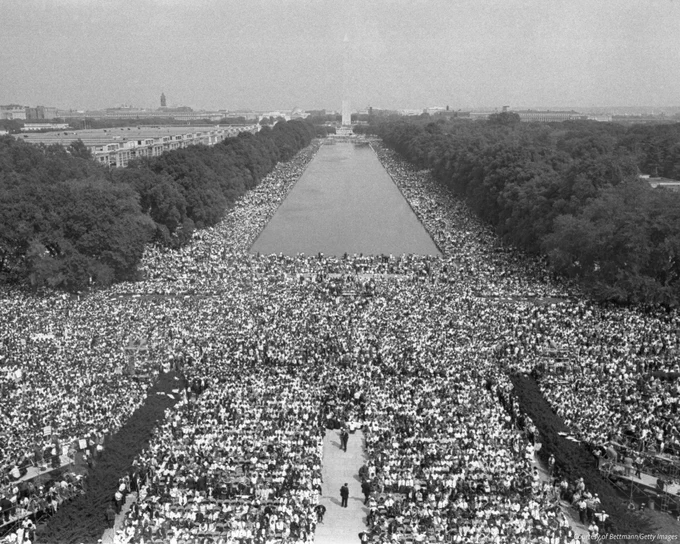 A black and white photo taken from the top of Lincoln Memorial shows the March on Washington crowd on August 28, 1963. The crowd on the National Mall is filled out in front of the Memorial and on either side of the Reflecting Pool. 