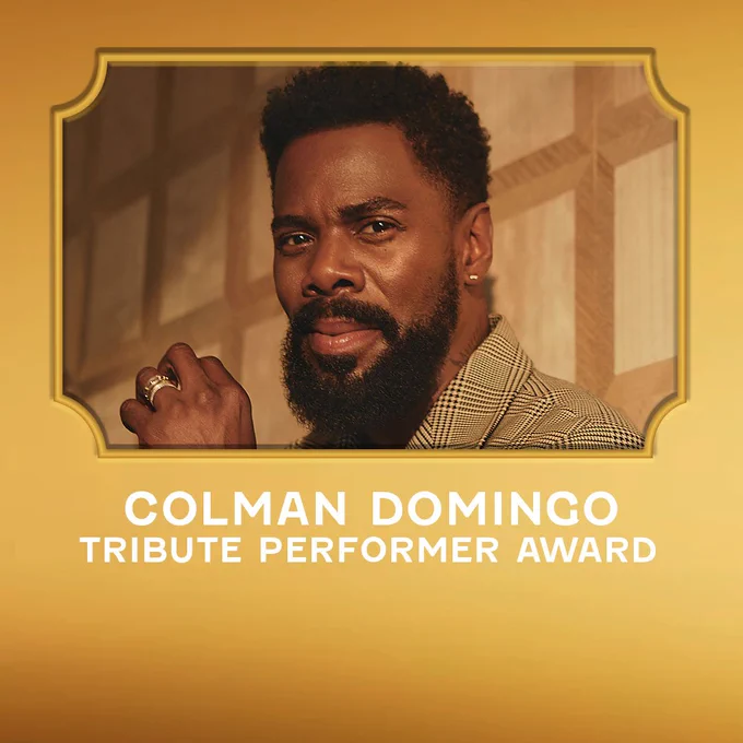 A golden design asset featuring a photo of Colman Domingo. He is wearing a patterned jacket and holding his hand up near his face, posing in front of a beige patterned backdrop. The below reads “Colman Domingo, Tribute Performer Award”.