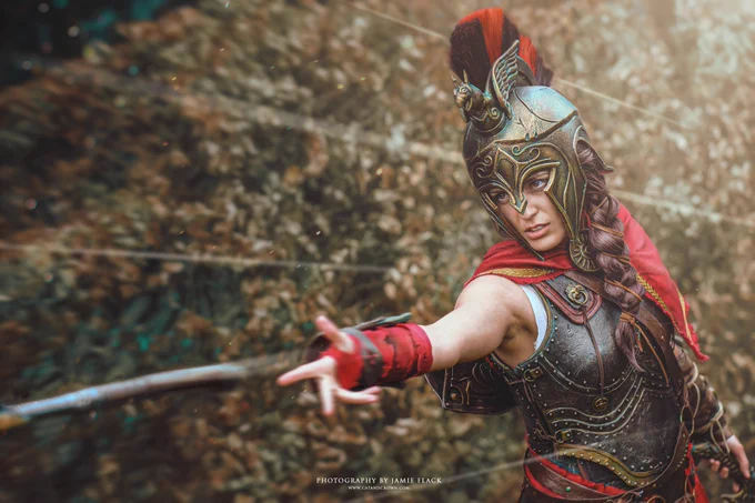 A photo of a cosplay of Kassandra from Assassin's Creed Odyssey, posed throwing her spear.