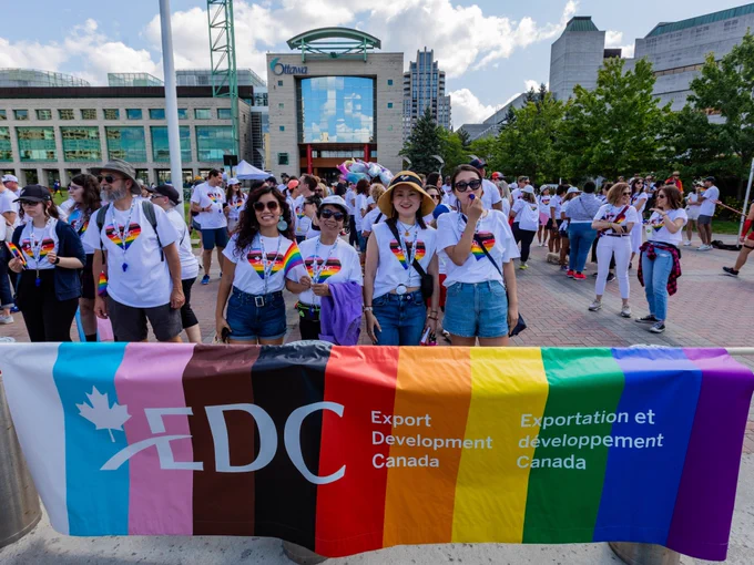 A group of employees from Export Development Canada posing for a photo together with a colourful banner that reads: EDC – Export Development Canada. Exportation et développement Canada.