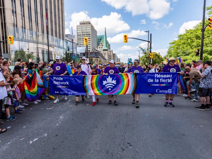 A group of participants marching in the Pride Parade and holding a banner that reads: Pride Network – Shared Services Canada. Réseau de la fierté – Services partagés Canada.