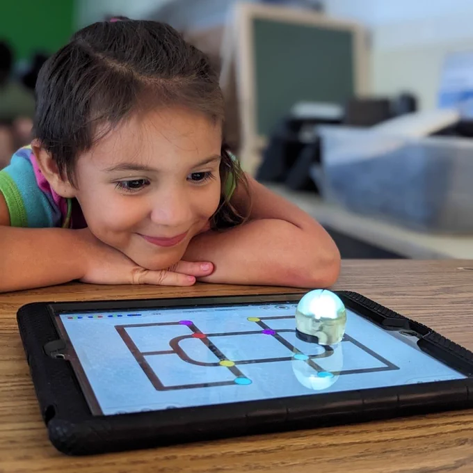 Student using a small robot on an iPad 