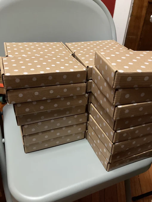 Stacks of brown boxes with cute white polka dots on them sit on a chair ready to be sent out