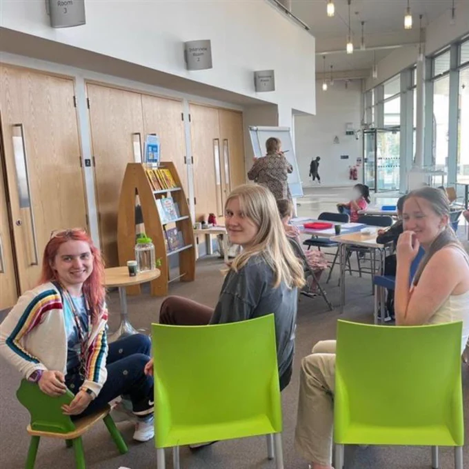 a fun-looking event at addlestone library. sharon's drawing something on a flipchart, lots of kids and adults are watching, and hannah and the volunteers have turned round to face the camera.