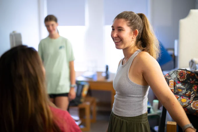An image of three people standing in a dorm room.