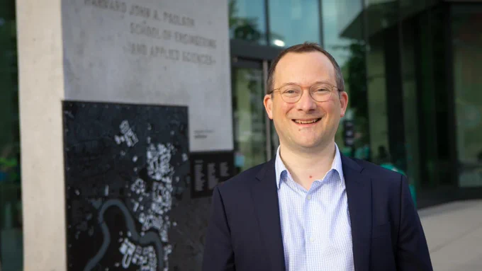 David C. Parkes, George F. Colony Professor of Computer Science and newly appointed SEAS dean, in front of a sign for the Harvard John A. Paulson School of Engineering and Applied Sciences at the Science and Engineering Complex in Allston