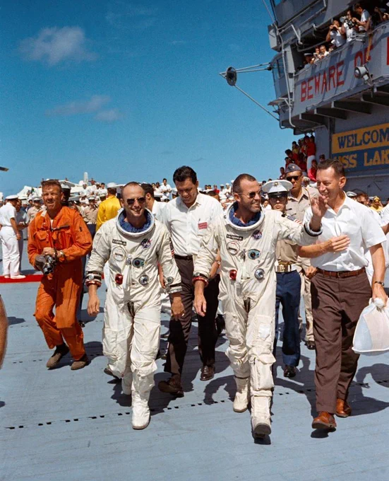 Gemini V astronauts Gordo Cooper (right) and Pete Conrad (left), along with several other men, walk across the deck of the aircraft carrier USS Lake Champlain following recovery of their Gemini spacecraft from the ocean. Date taken August 29, 1965. Credit: NASA
