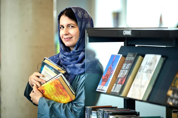 Photograph of Ioana holding a couple of books in a Manchester Library
