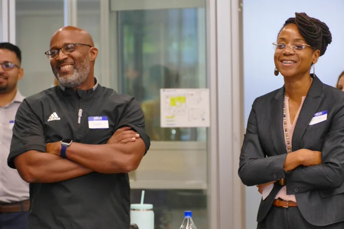 Two people, each with their arms crossed, laugh.