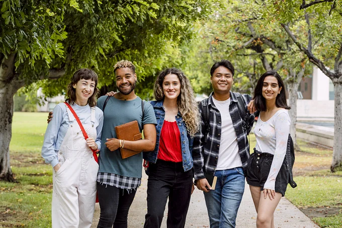 Group of diverse student standing on a path outside and smiling