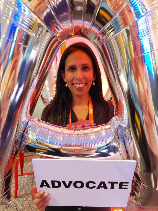 Jessica Schibli with a sign that says 'Advocate', posing with an inflatable silver A.