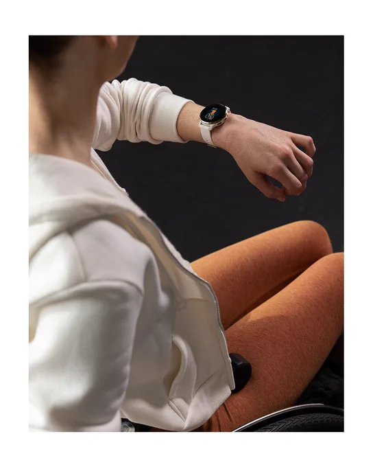 A woman sitting in a wheelchair checks her Venu 3 smartwatch while working out in a gym.