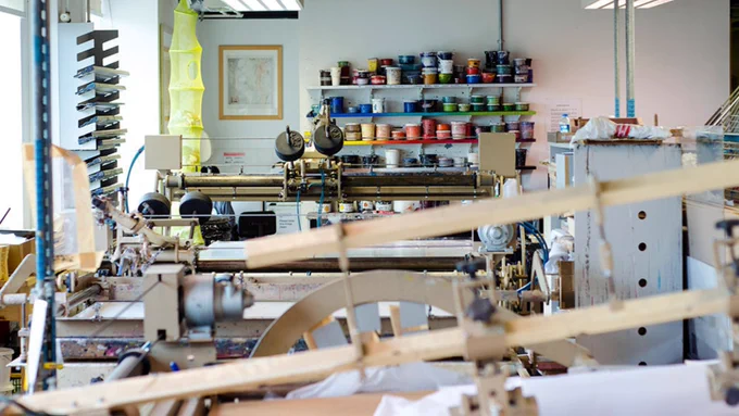 Inside DCA Print Studio. Printing machinery covers the space and pots of coloured ink line the back wall. 