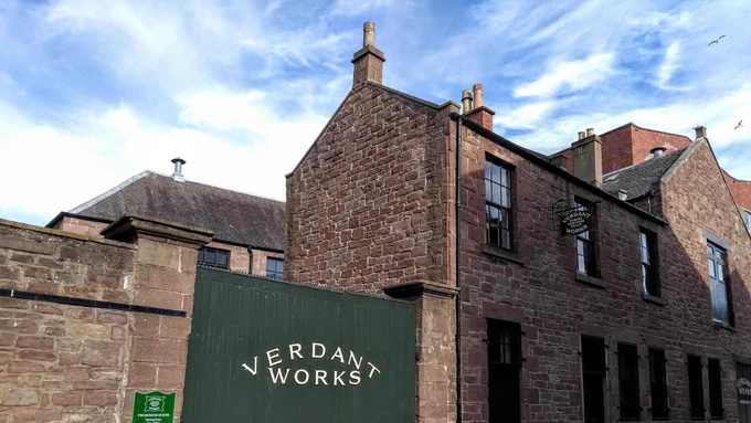 Outside of Verdant Works. The museum's name is painted in white on the large green entryway gate. 