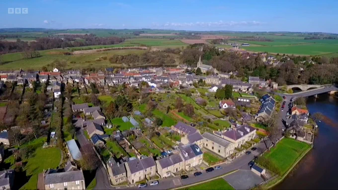 Aerial view of a village, showing long, thing plots with house at street frontage.