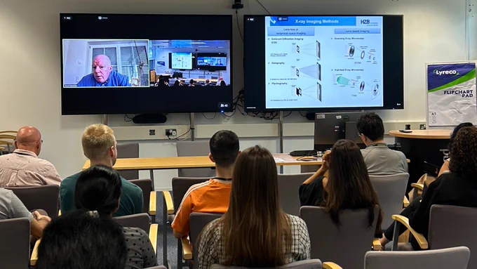 A photo of a hybrid meeting, where Gerd Schneider from HZB is speaking via video conference to a room of early career scientists