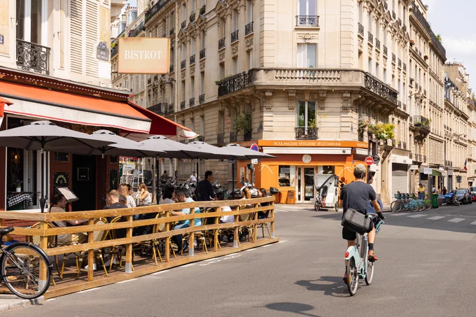 De nombreuses personnes sont assises en terrasse rue de Douai dans le 9e, pendant qu'un vélo passe sur la route.
Crédit : Guillaume Bontemps / Ville de Paris