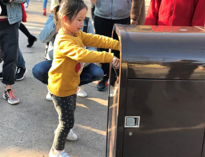Young girl placing garbage into a talking trash can at Shanghai Disneyland