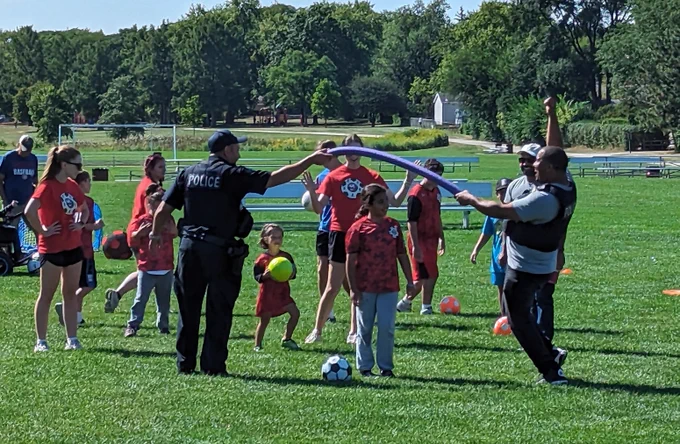 Two Schaumburg Police Officers hold a pool noodle for a drill and cheer for TOPSoccer participant. 