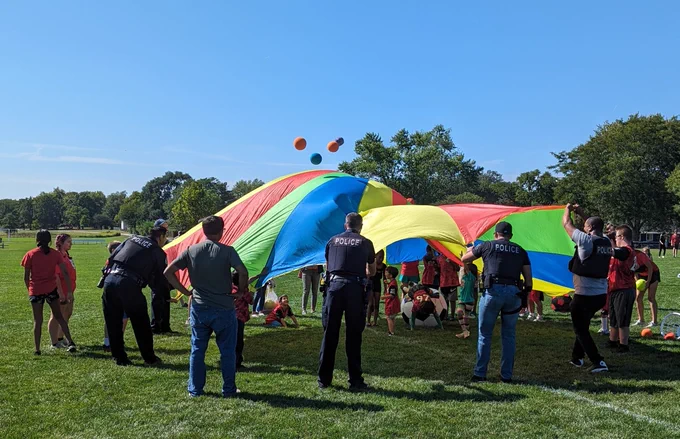 Schaumburg Police Officers and TOPSoccer coaches, buddies and participants play with a rainbow parachute. 