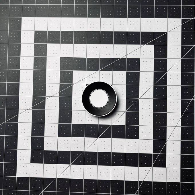 A circular rotary dial with a button in the center on a gray arts & crafts mat, the all-new Flic Twist