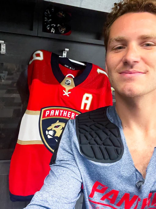 Photograph of Matthew Tkachuk taking a selfie in front of his red home jersey.