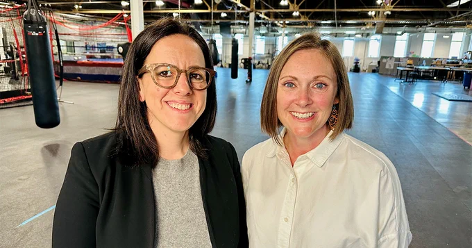 Two women standing together in gym