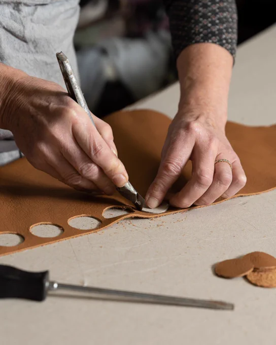 Mains d'une artisane travaillant le cuir dans son atelier