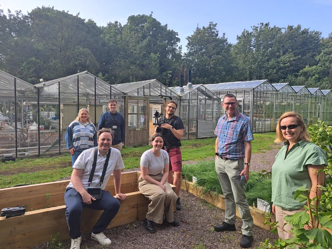 Group of people with glasshouses in the background