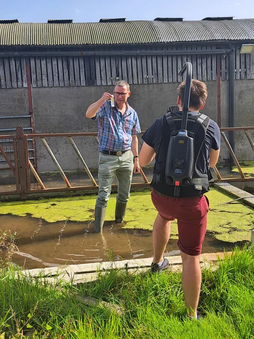 Two males by a pond of shallow water on a farm