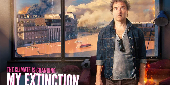 Film poster for 'My Extinction' with main character frowning stood in front of a window, behind him and through the window is a burning, smoking and flooded city. 