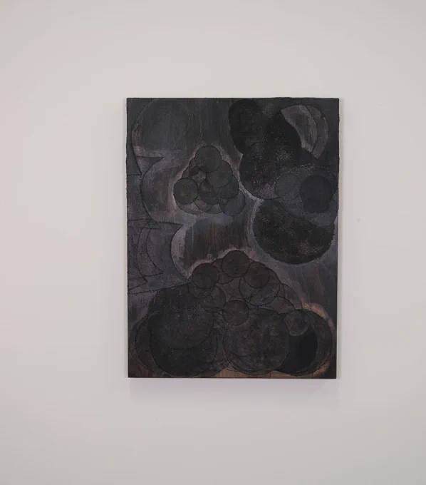 A deep grey and back collage with circular shapes on a white wall. 