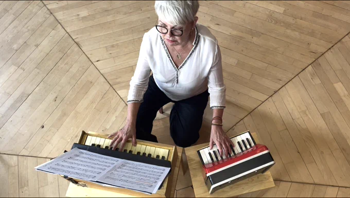 An aerial view of Kate playing two toy pianos: a Goldon and a Jaymar