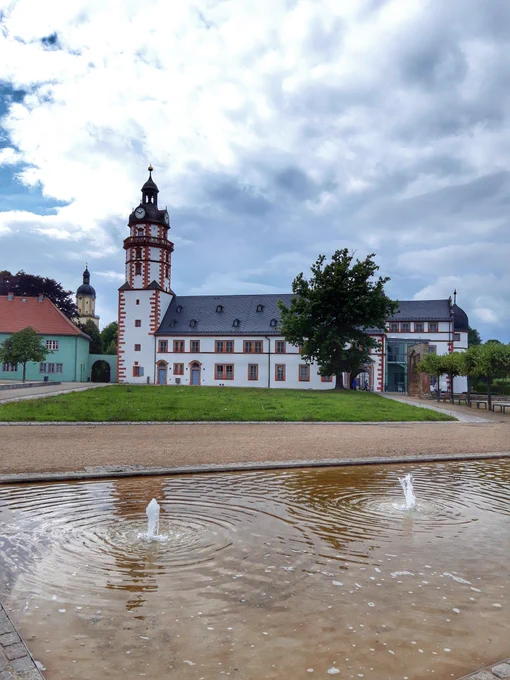 Schloss Ehrenstein in Ohrdruf, im Vordergrund ein Springbrunnen, Wolken am Himmel 
