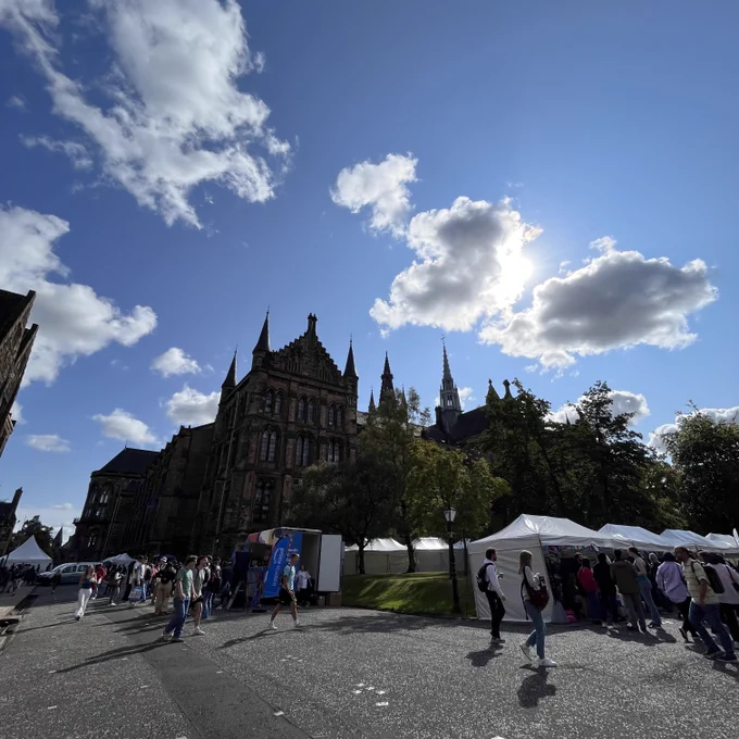 Blue sunny skies during the Welcome Fair in Professors Square. With stalls set up in front of the main building and students and freshers walking around campus and the tents. 