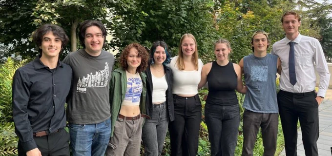 A group of eight college students standing together outside