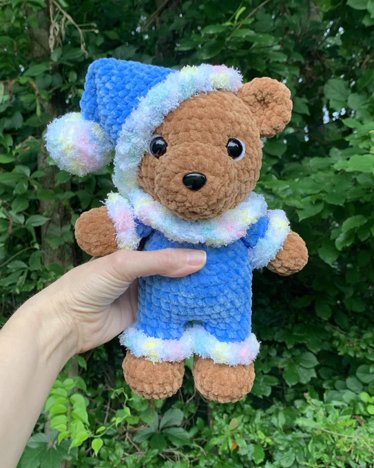 Brown crocheted teddy bear in blue jammies with a fuzzy ruffle