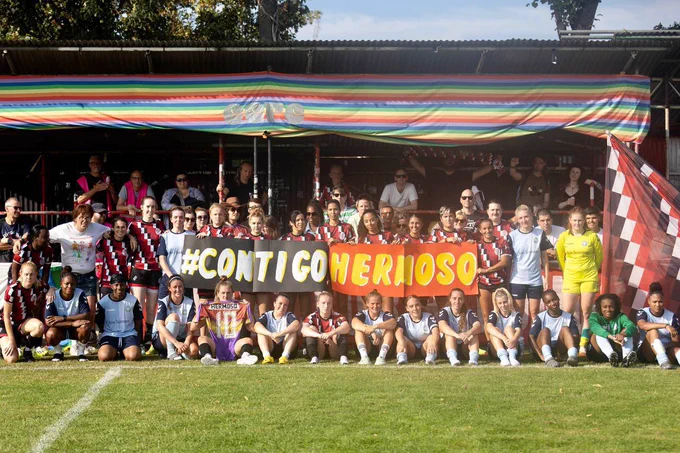CCFC women's first team holding a banner saying #CONTIGOHERMOSO at the Old Spotted Dog Ground