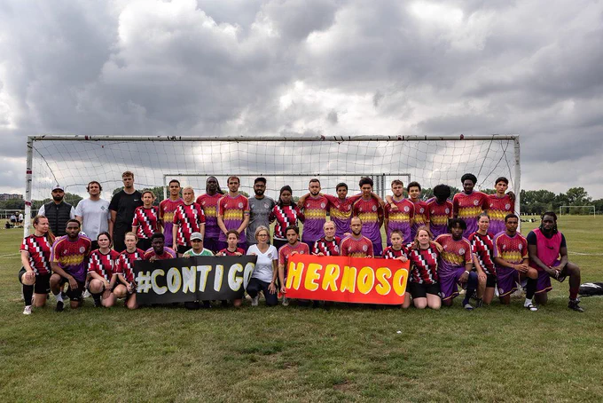 CCFC development teams holding a banner saying #CONTIGOHERMOSO at the Hackney Marshes
