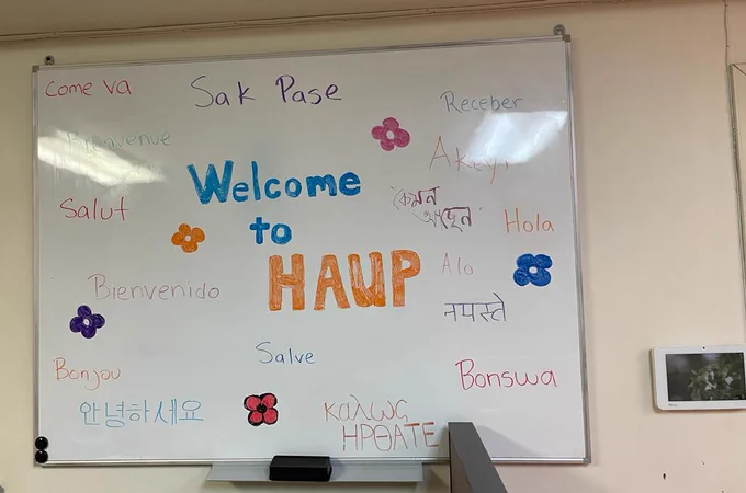 Inside an office there is a dry erase board with the words "welcome to HAUP" in different languages. 