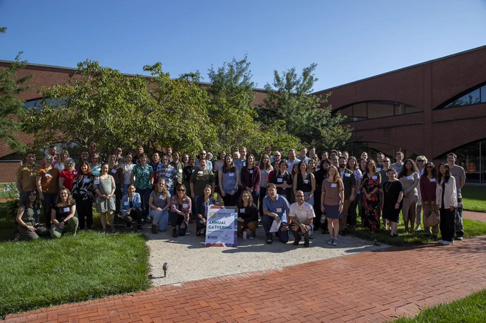 Large group of people standing in a courtyard on a sunny day. 