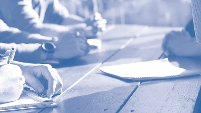 Hands of people sitting together at a table, working collaboratively. Photo: Unsplash