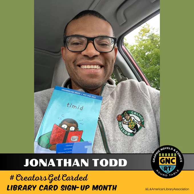 Comics creator Jonathan Todd smiling and holding up his book TIMID and his library card.