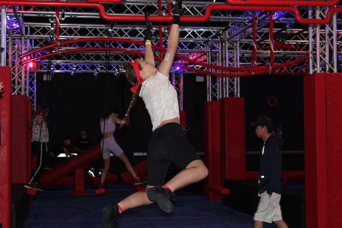 The image shows a young girl swinging on monkey bars. 