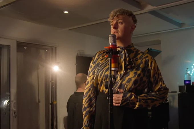 A photo showing a performer in front of a microphone in a studio