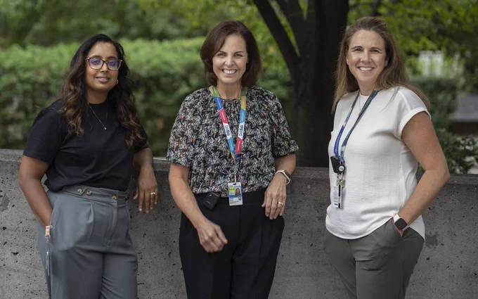 Clinical Nurse Specialists Vandana, Denise and Shaun stand in front of a tree, leaning against a cement wall.