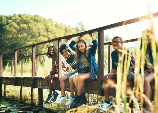 a group of diverse teens sitting on a dock smiling